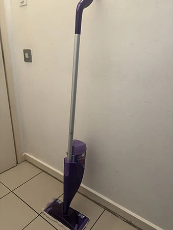 Front view of a Flash mop showing it's grey pole, purple handle, mop head, and cleaning solution